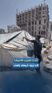 עקורה מתיז מים על אוהלו בעיר עזה; כדי לנסות להקל על ההשפעות של חום הקיץ הלוהט.