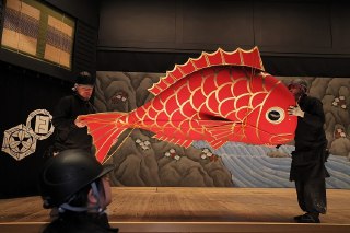 【日本通过2026财年预算案】大阪国立文乐剧场工作人员安装「红鲷鱼」新年装饰布景，日本。12月26日，日本内阁会议通过2026年度财政预算草案，总额达122.3万亿日元（约合7846.3亿美元），比2025财年增加6.3%，创下历史新高，其中社会保障开支增加30%至逾39万亿日元，国防开支增加3.8%至9万亿日元，用于赎回或支付政府债券利息的支出达31.2万亿日元。这是日本首相高市早苗上任以来出台的首份完整财年预算。日本内阁府预测2026财年该国实际 GDP 增长率为1.3%，较2025财年提升0.2个百分